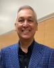 Photo of Dr. David Reyes in a blue and black blazer and black shirt. 