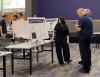 Photo of a student presenting their poster board to a fair vistor