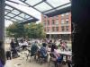 A group of students sits outside on an open air porch on campus.