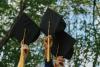 Photo of graduating students holding their graduation caps in the air