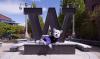Hendrix the husky mascot sitting in front of steel W sculpture