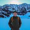 Image of student smiling in the snow with a mountain range in the background